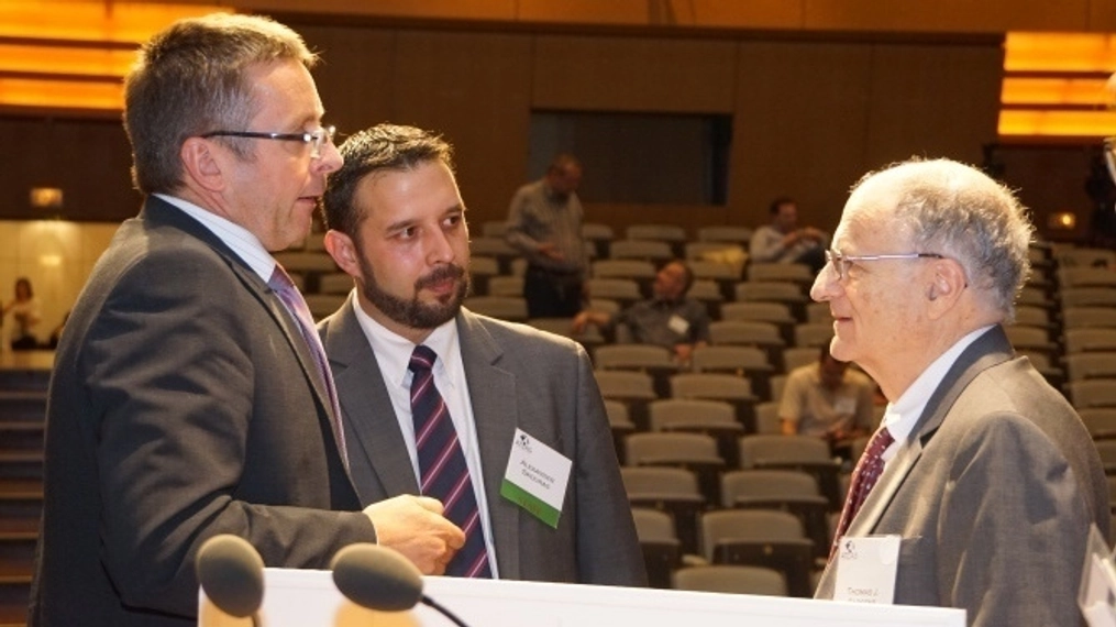 Ivan Miklos in conversation with two men wearing suits.